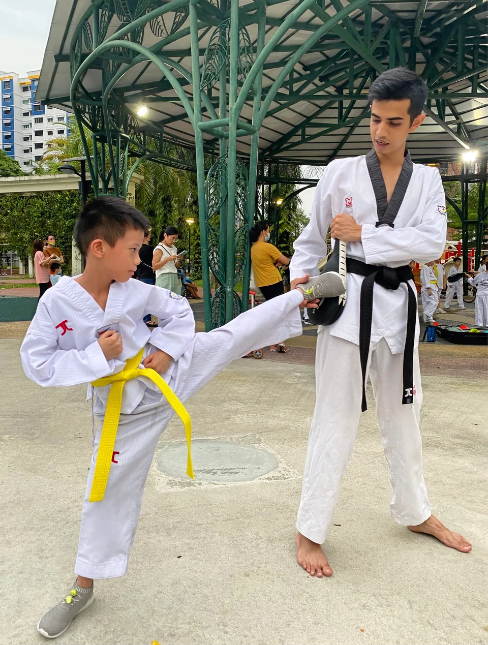 A Momentum coach patiently guides a young student through a side kick